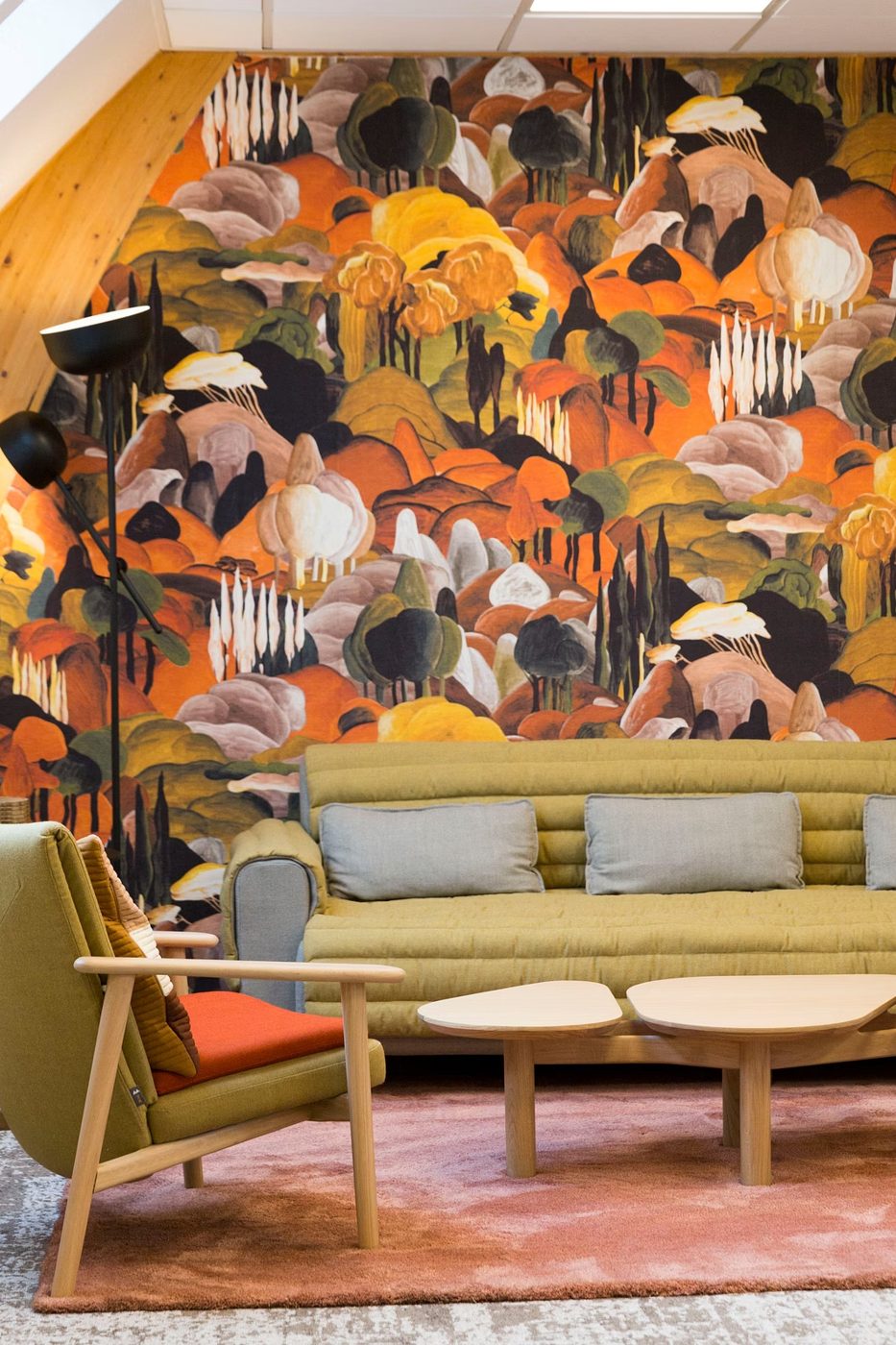 Salon d’hôtel avec papier peint paysage et canapé vert